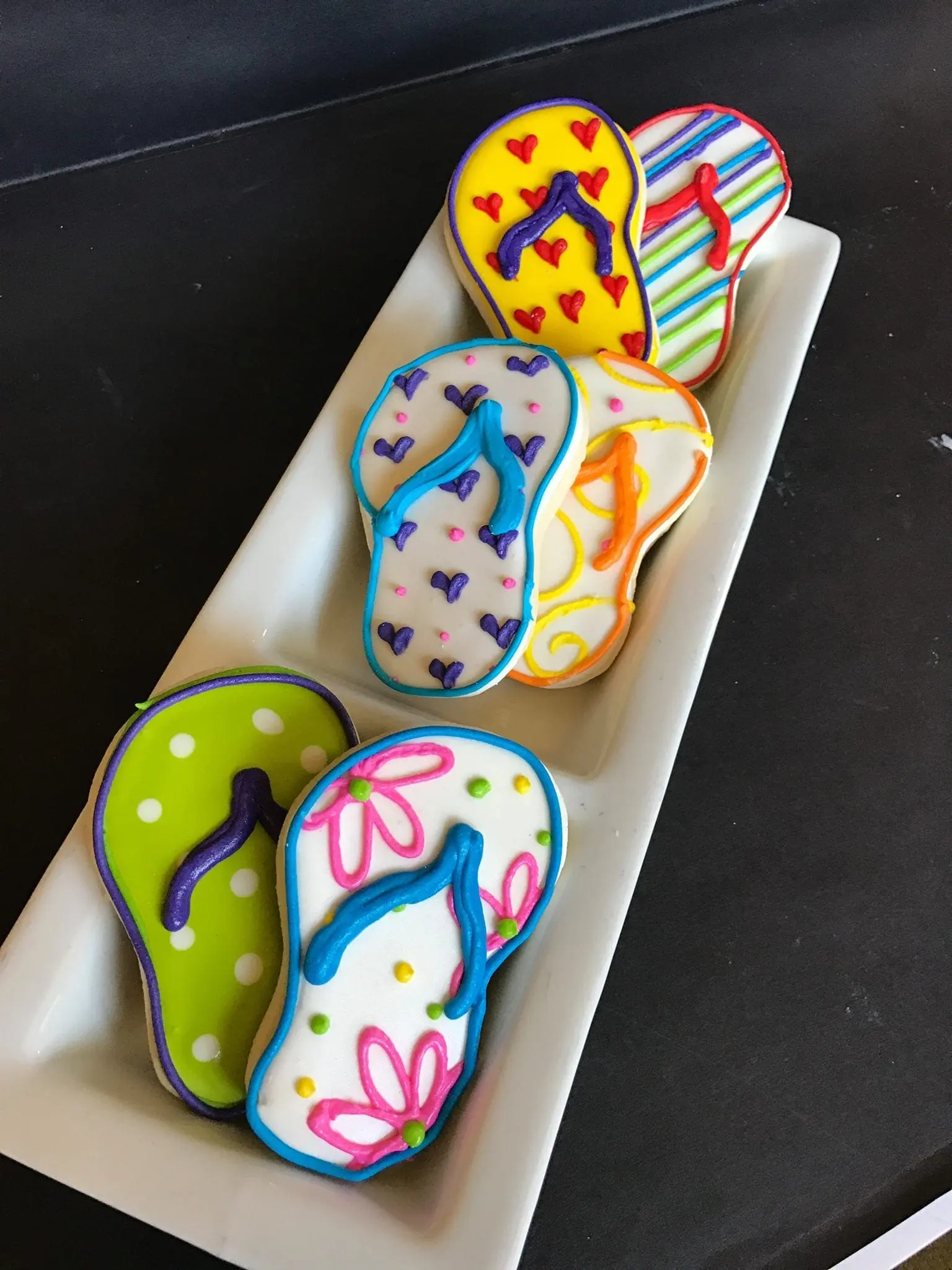 Flip-flop cookies with colorful designs on a white platter.