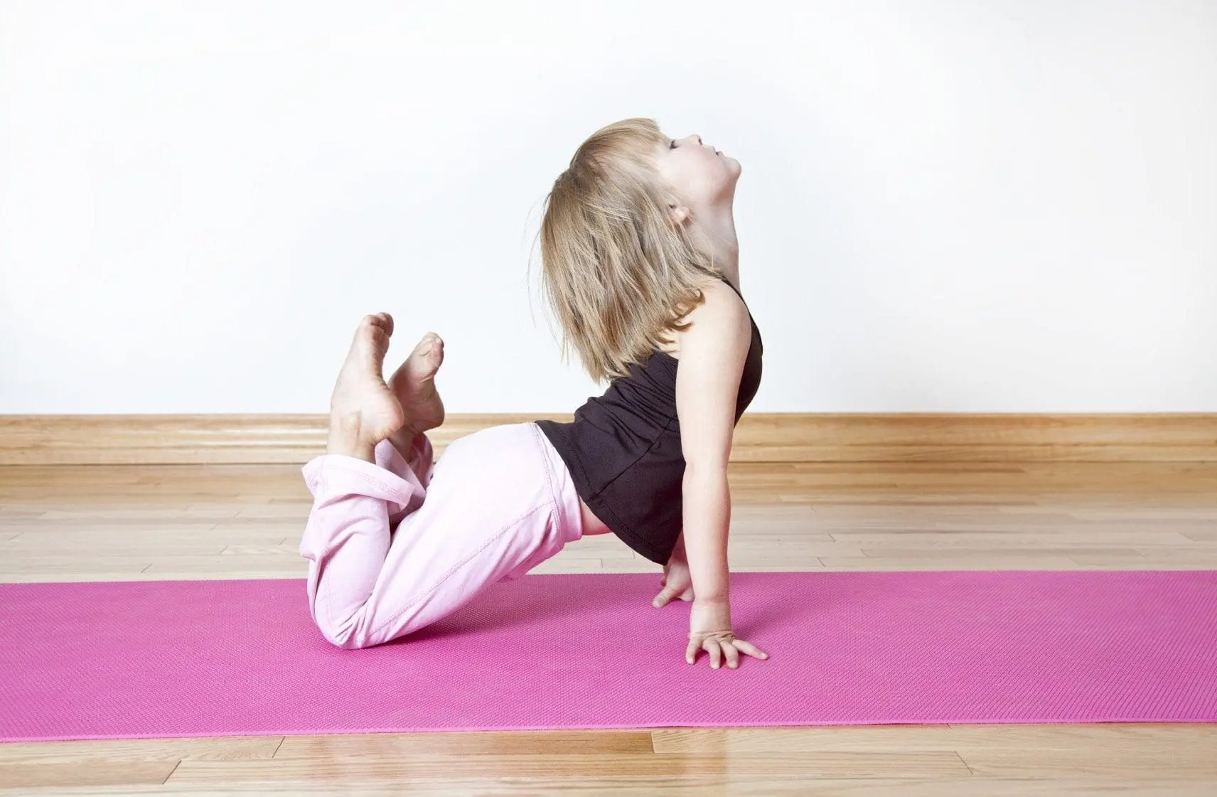 Young child in a yoga pose on a pink mat.