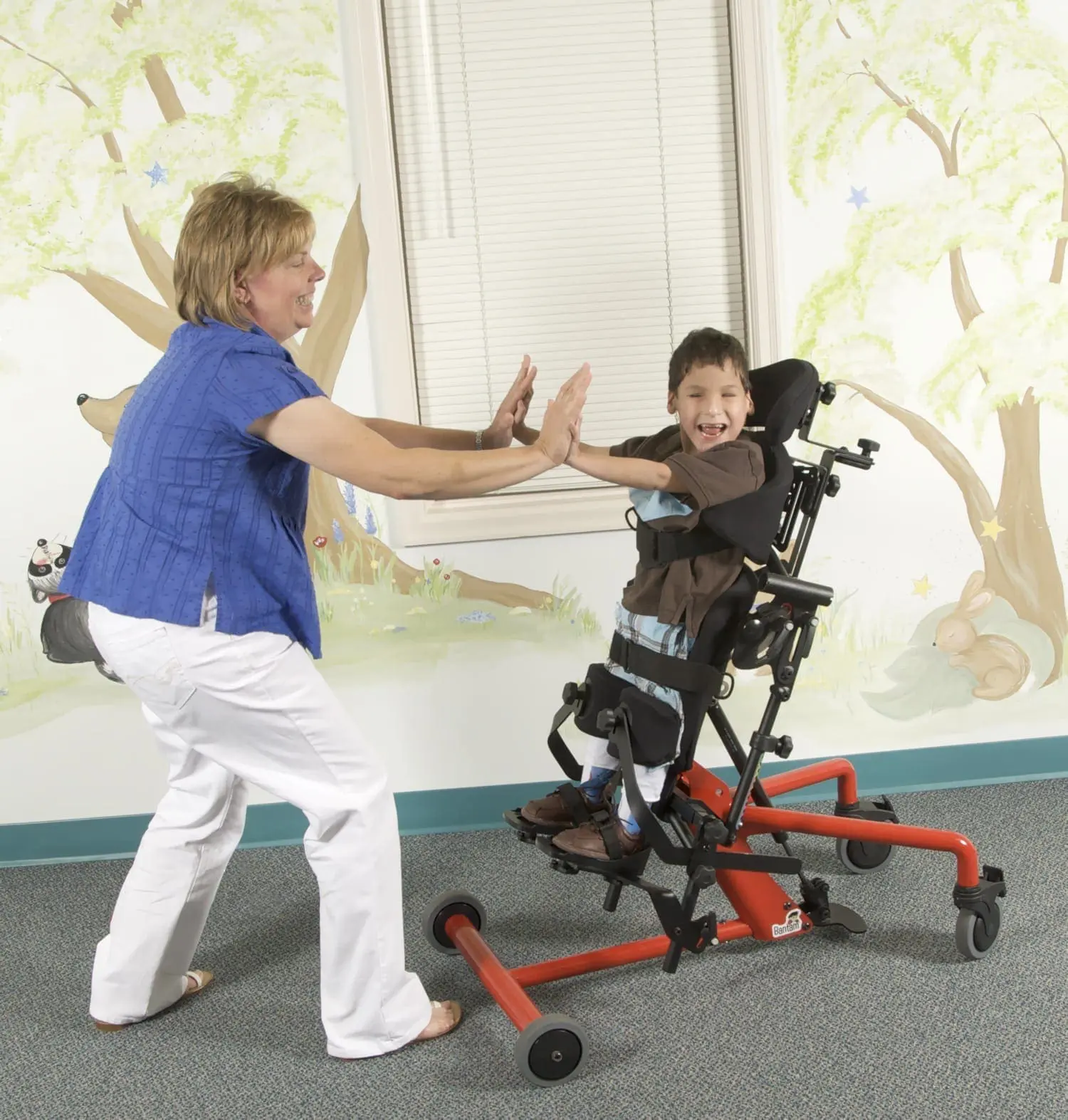 Woman high-fiving a boy in a standing frame.