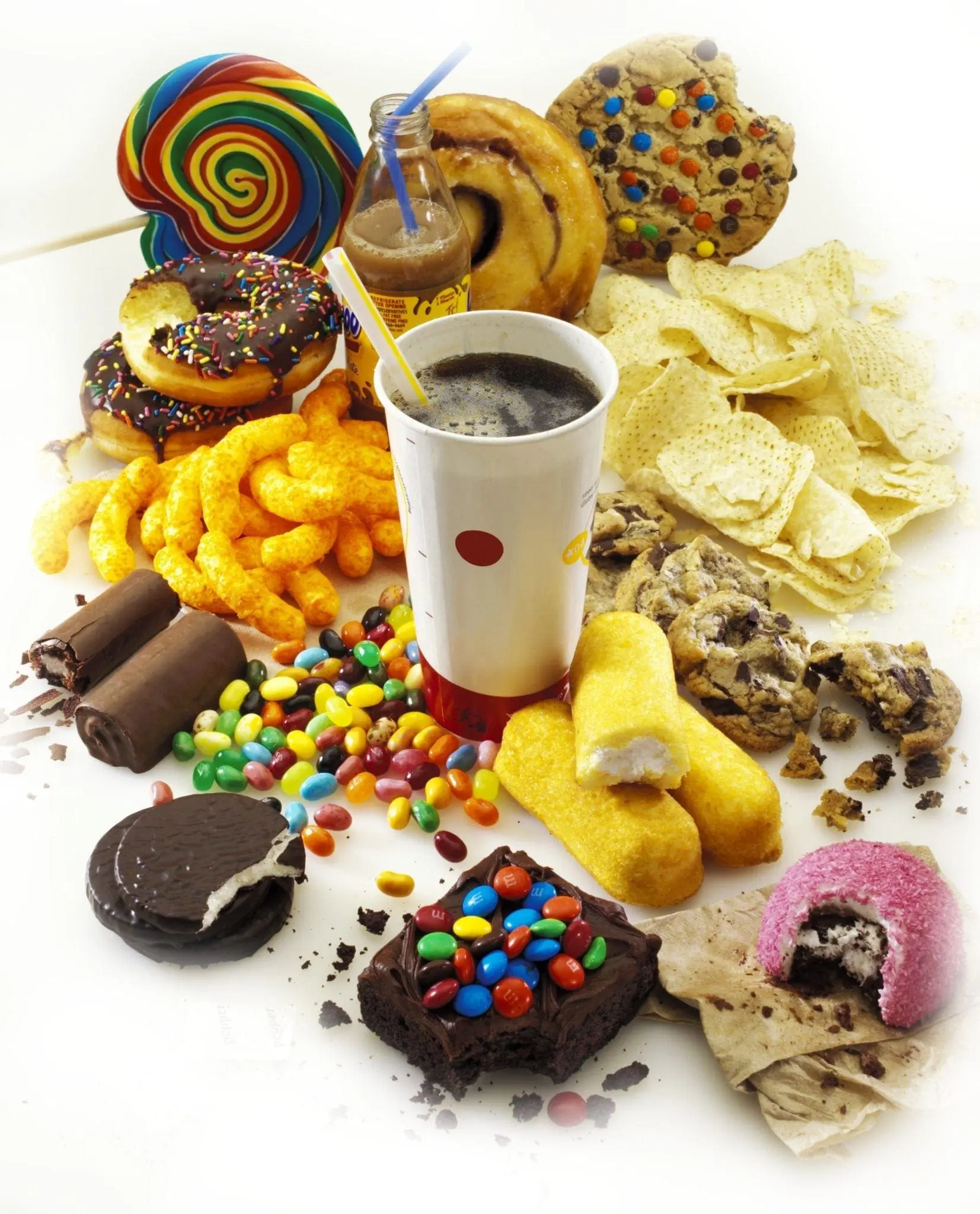 Assorted junk food including candy, donuts, chips, and a drink.