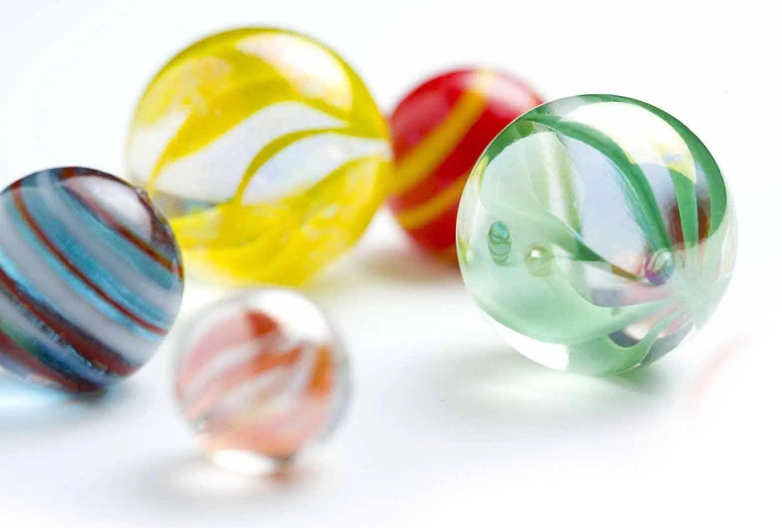Several colorful glass marbles on a white surface.