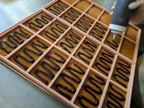 Chocolate drizzle being applied to a waffle mold.