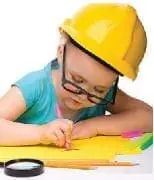 Child wearing a yellow hard hat and glasses draws on a yellow sheet of paper.