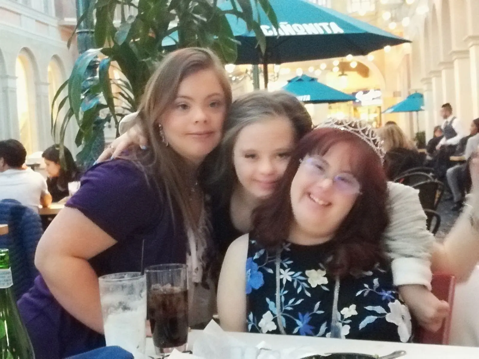 Three women smiling in a restaurant setting.