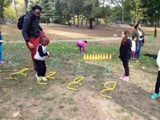 Children participate in an outdoor obstacle course with an instructor.