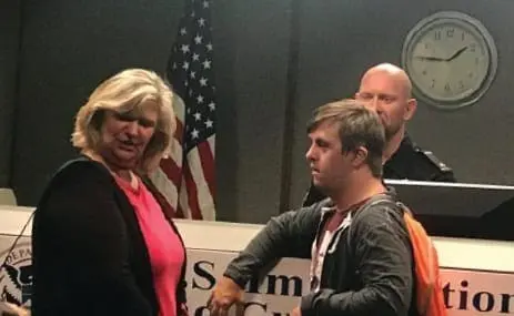 Sean McElwee and two other people stand near a desk with a clock on the wall.
