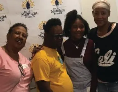 The John Tucker family poses for a photo in front of a backdrop.