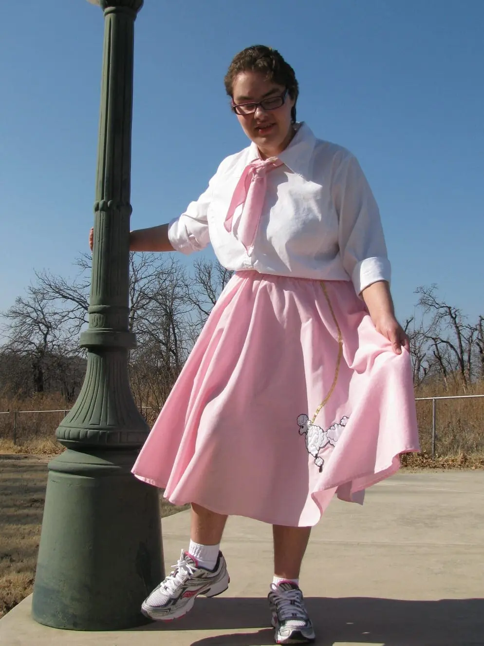 Angela Norris posing outdoors in a pink poodle skirt and white shirt.