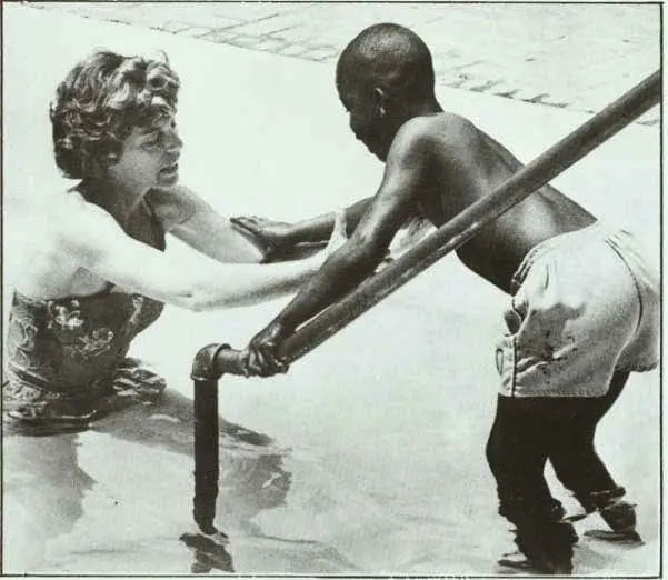 Eunice Kennedy Shriver assisting a child in the water.