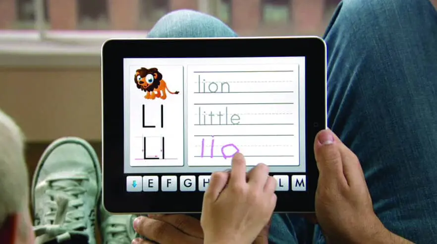 Child using a tablet to practice writing the letter L