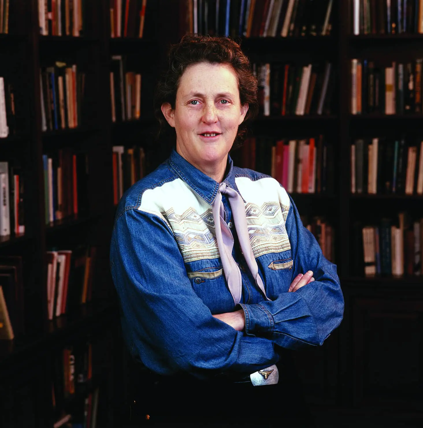 Temple Grandin standing in front of bookshelves.