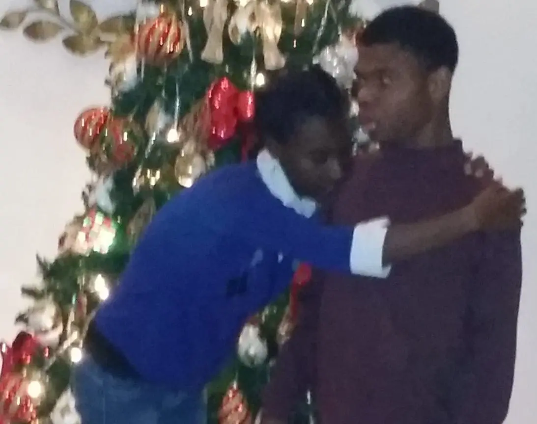 Debra Newman with a young man in front of a Christmas tree.