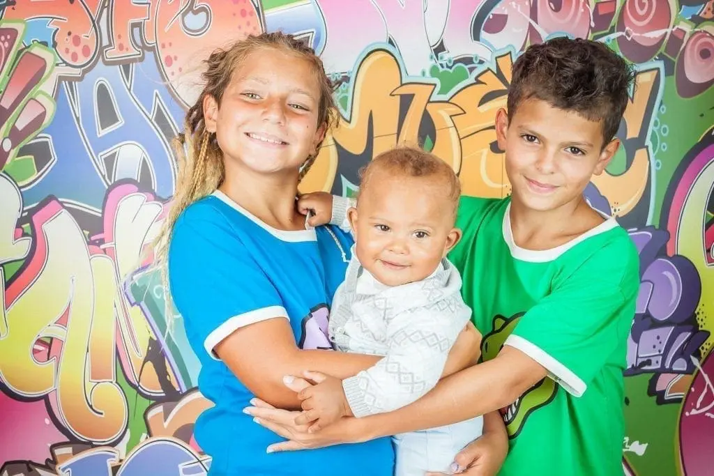 Elisha Von Haidenthaler Family with two children holding a baby against a graffiti wall.