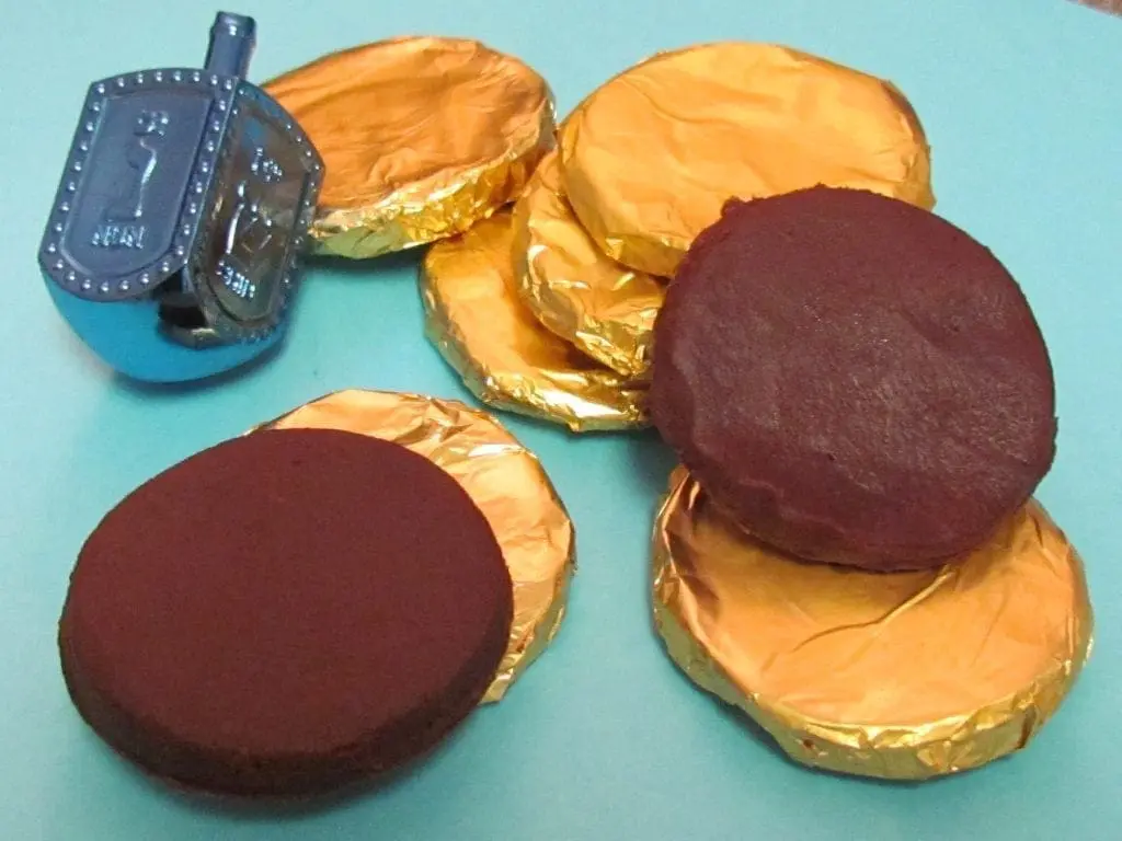 A blue dreidel and several chocolate coins wrapped in gold foil.