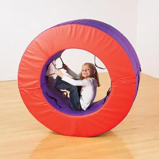 Girl in a large, padded, circular tunnel with purple and red sections.