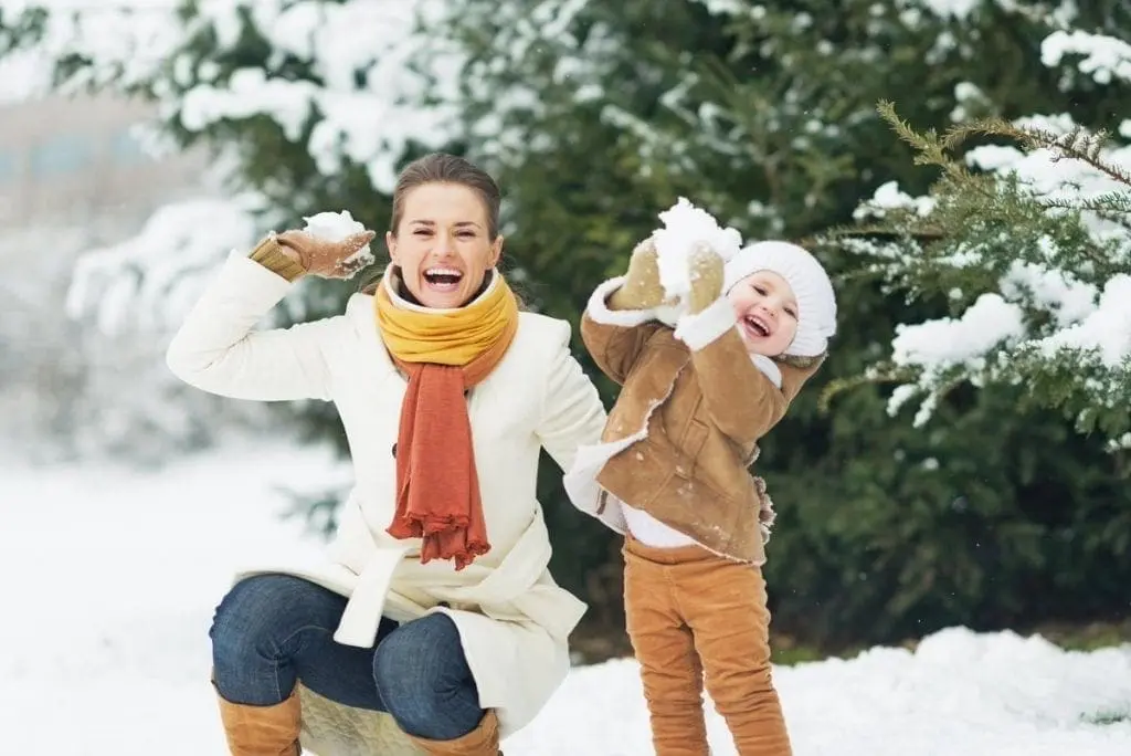 Woman and child throwing snowballs in a snowy outdoor setting.