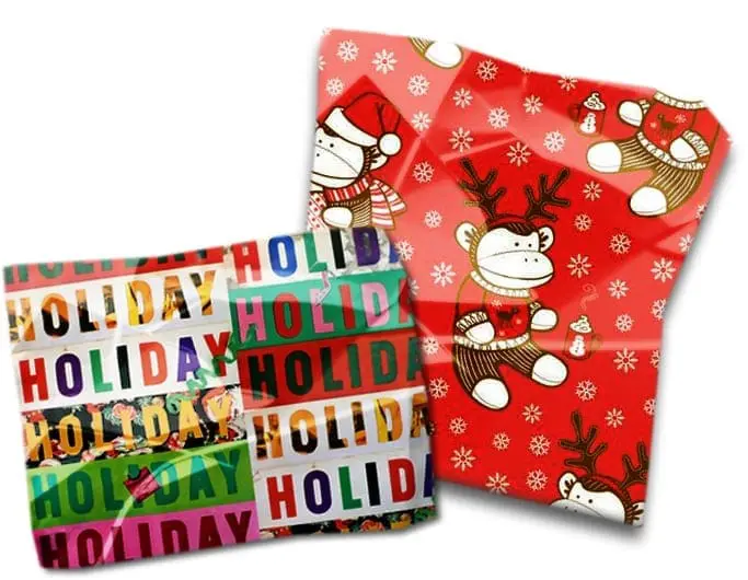 Two sheets of holiday wrapping paper, one with a repeating "HOLIDAY" pattern and another with sock monkeys in Christmas attire.