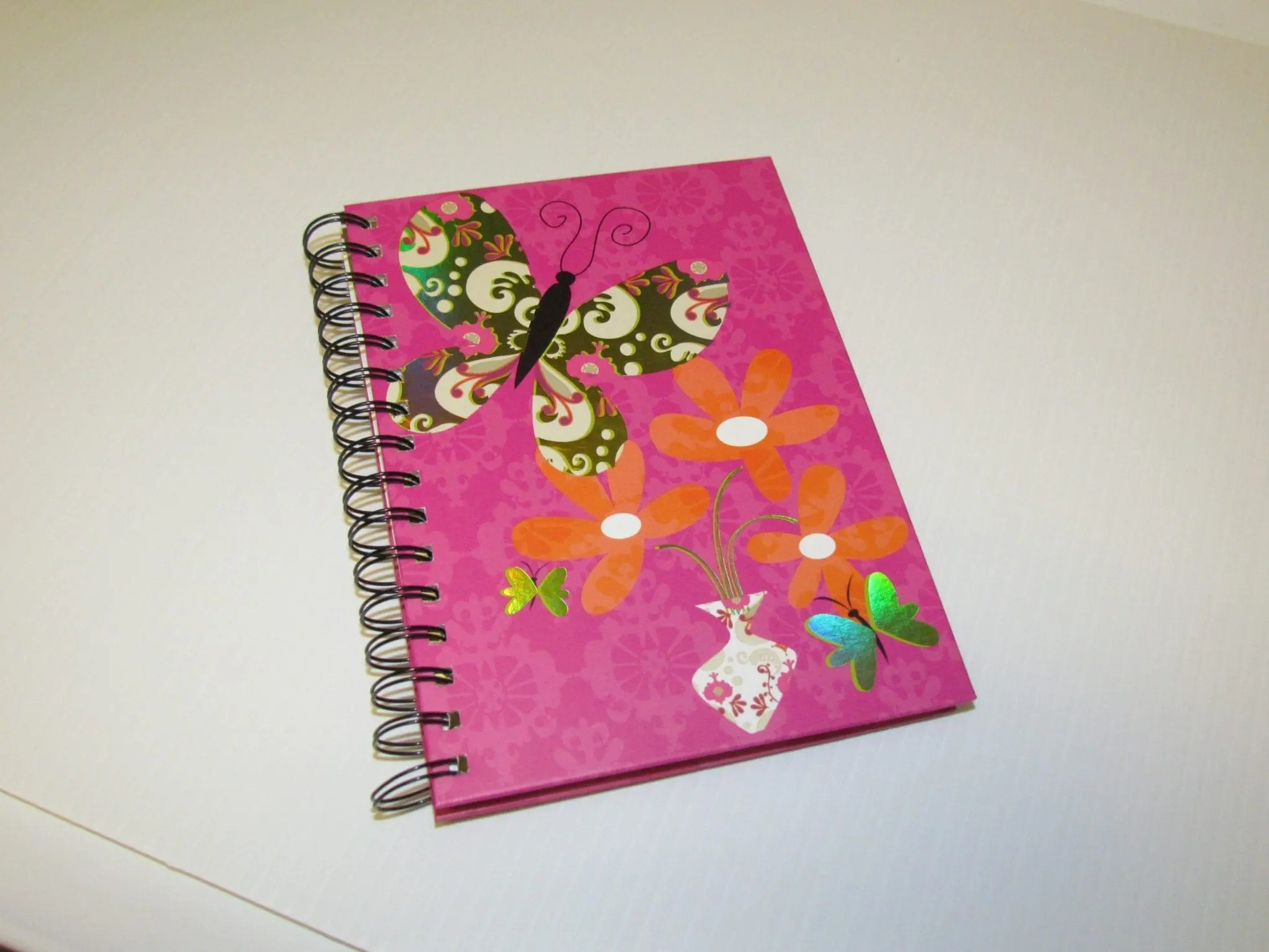 Pink happiness journal with butterfly and flower decorations.