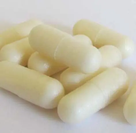 A close-up of several white probiotic capsules.