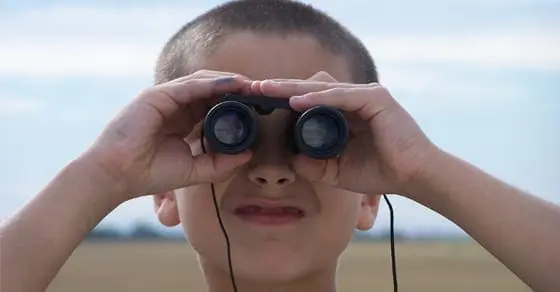 Boy looking through binoculars with a blurred background