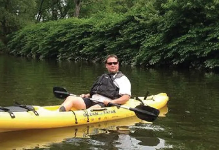 Man in a yellow kayak on a calm body of water.