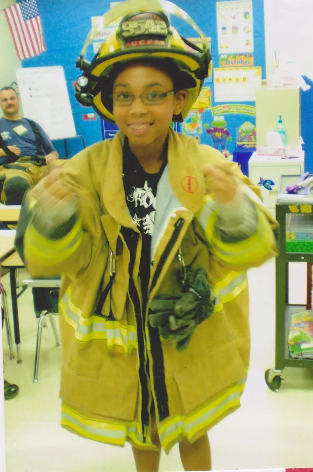 Child in firefighter costume with an American flag in the background.