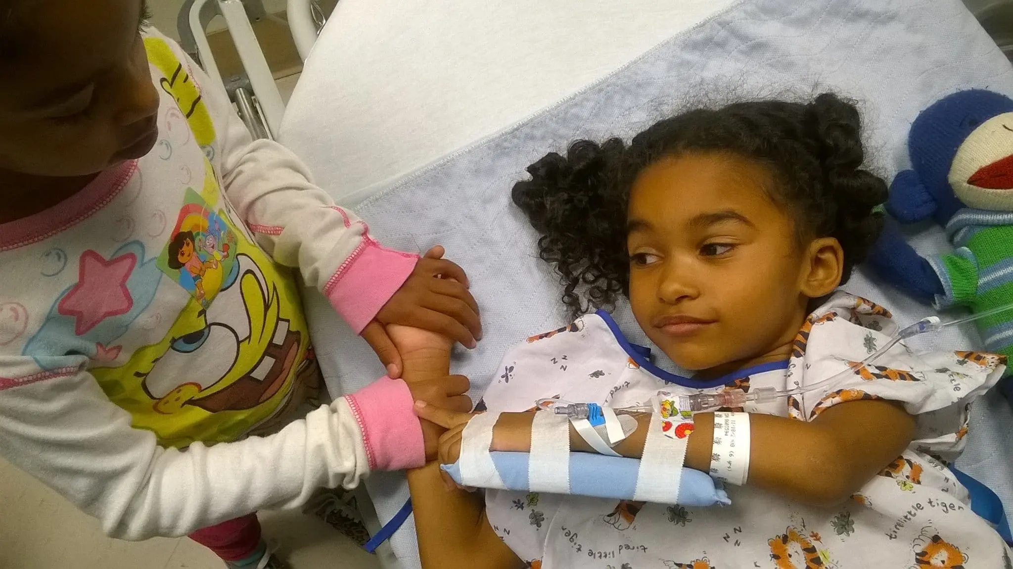 Jada and Maya holding hands at the hospital.