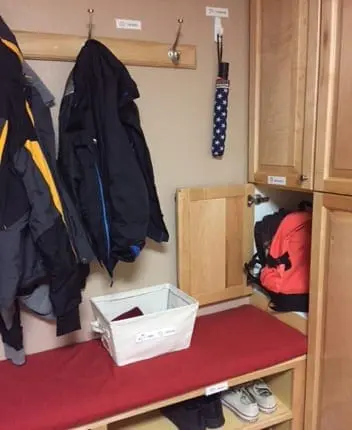 Coat rack with jackets, bench with shoes, and storage cubbies.