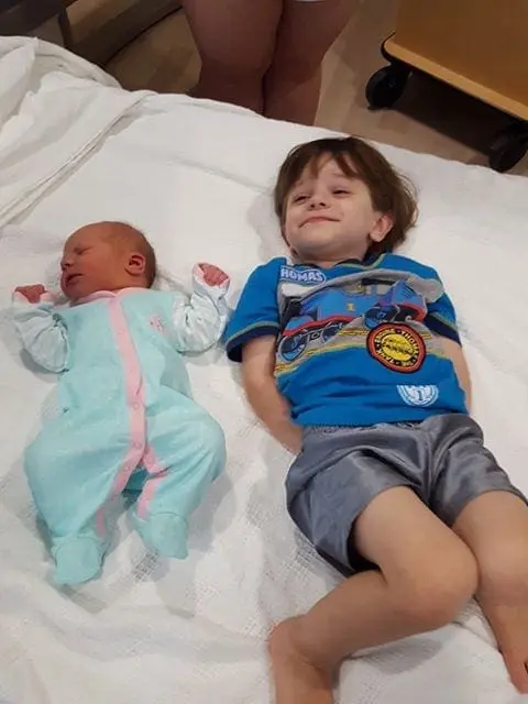 Malachi Roth, an autistic boy, gently pats his baby sister Millie's belly.