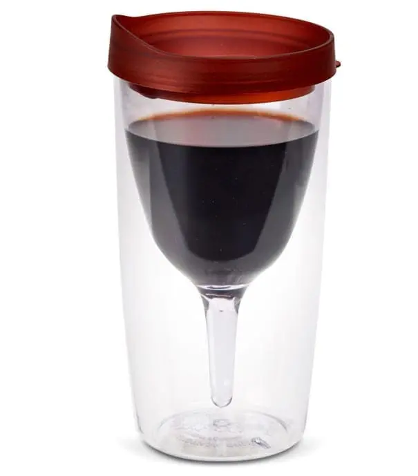 Clear tumbler with red lid and a wine glass inside filled with red wine