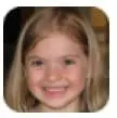 A young girl with blonde hair smiles at the camera.