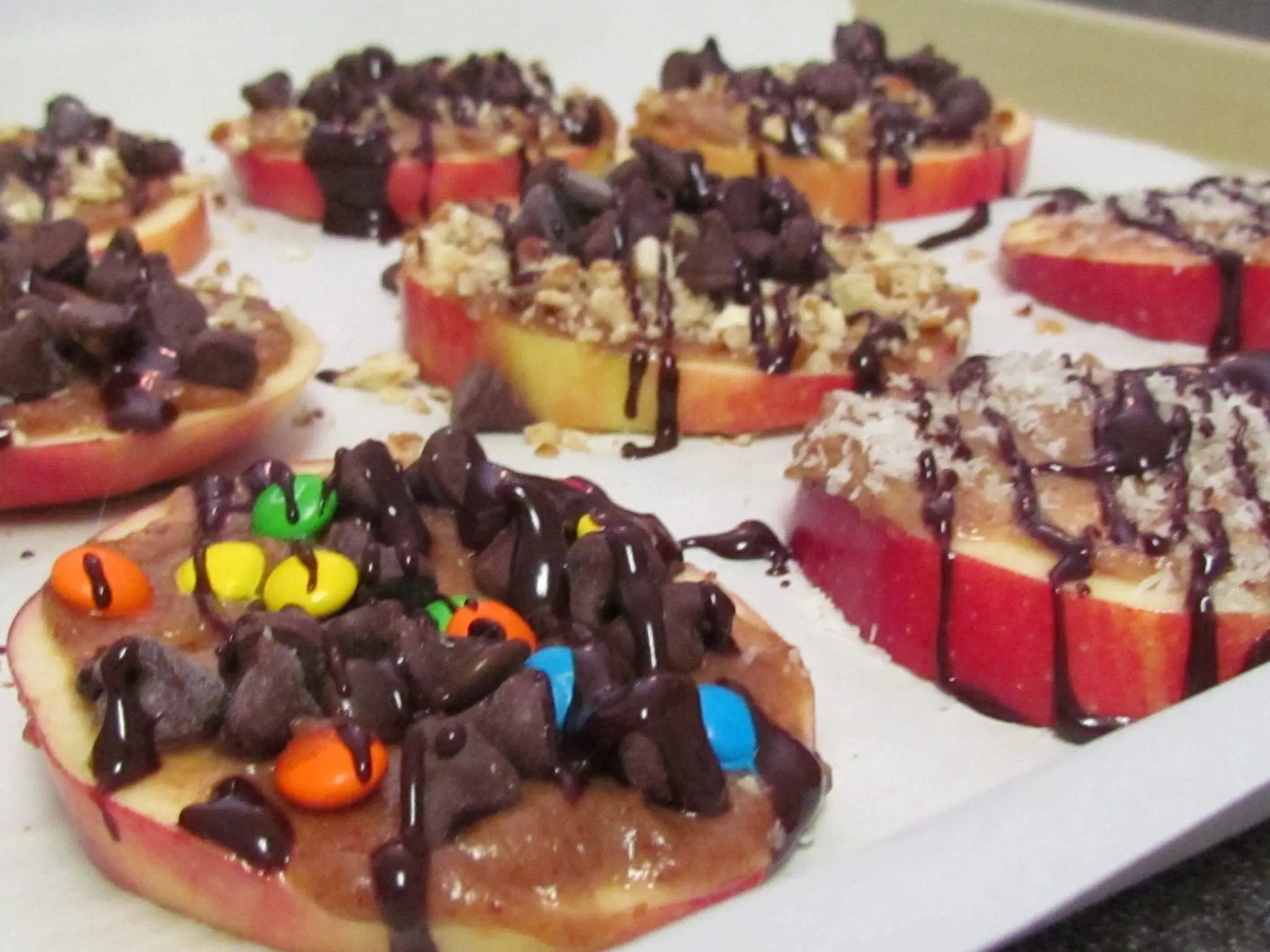 Apple slices topped with peanut butter, chocolate chips, and candy.