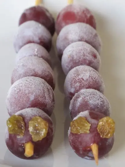 Two grape skewers decorated to look like elephants.