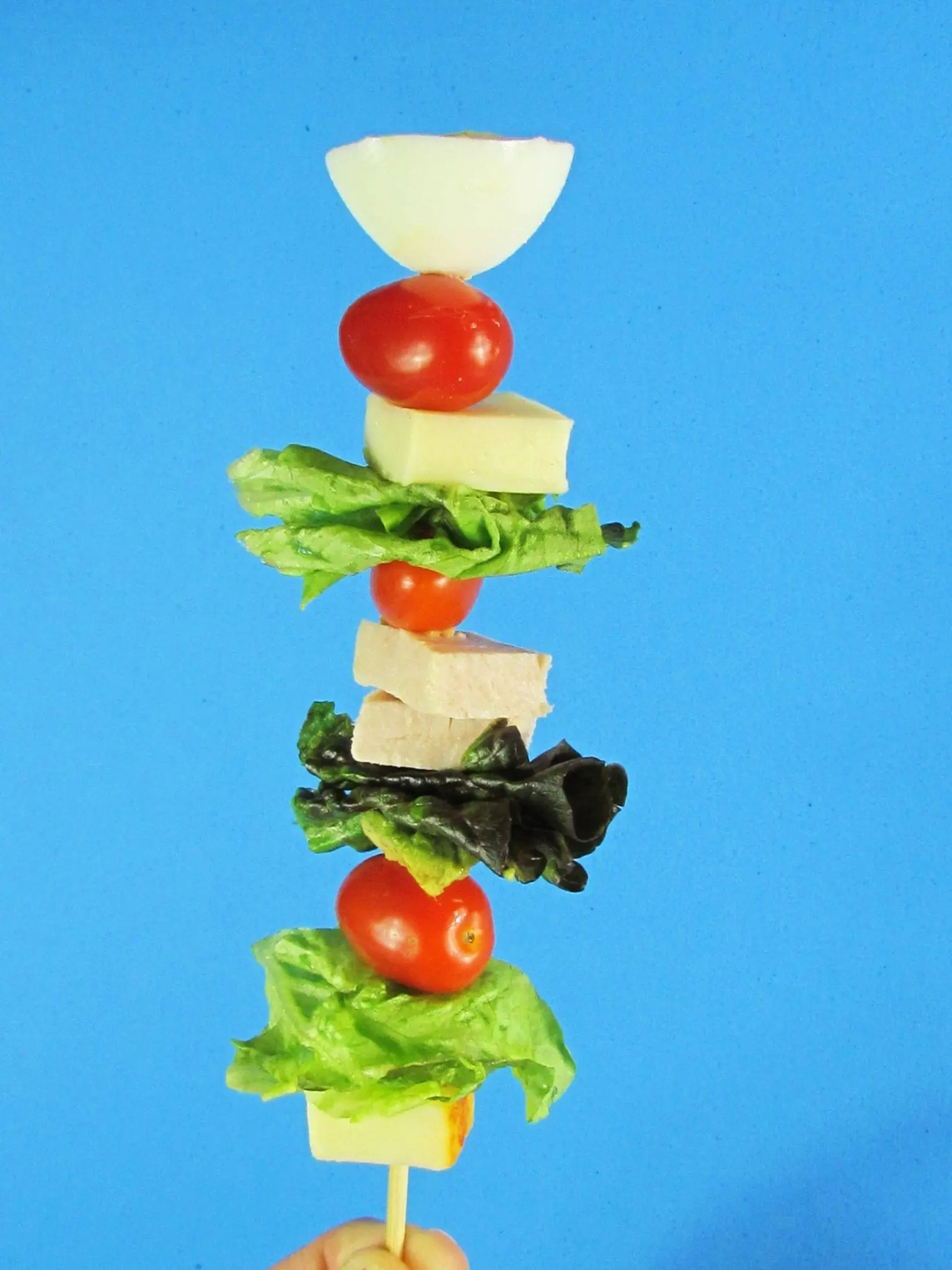 Kiddie Cobb Salad on a stick with lettuce, tomatoes, cheese, and hard-boiled egg.