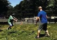 Two people playing catch with medicine balls in a park.