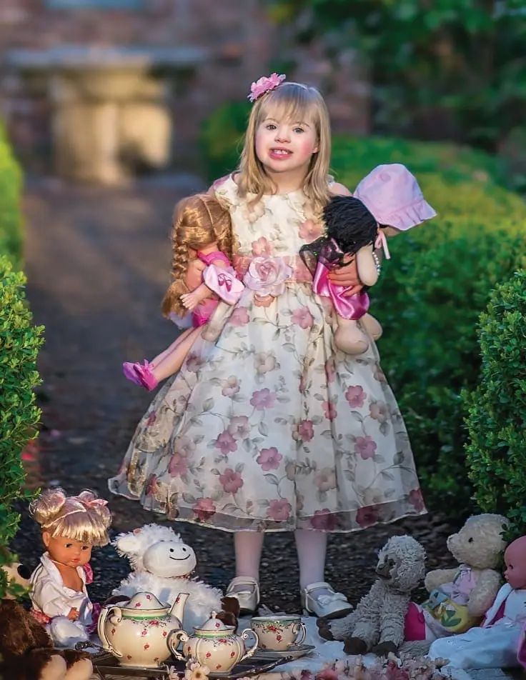 Amelia Grace Vitacco holding dolls and surrounded by toys.