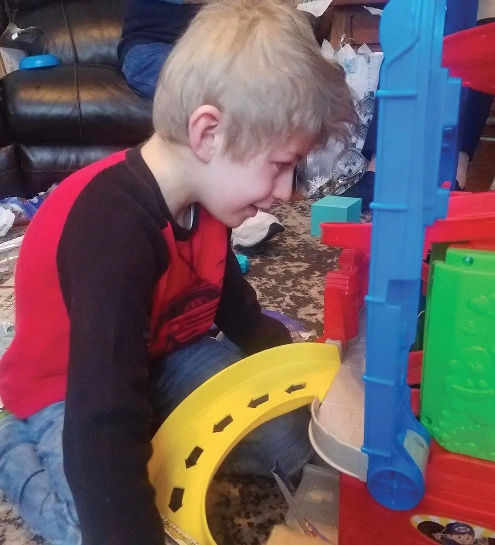 Boy playing with a toy car ramp and playset.