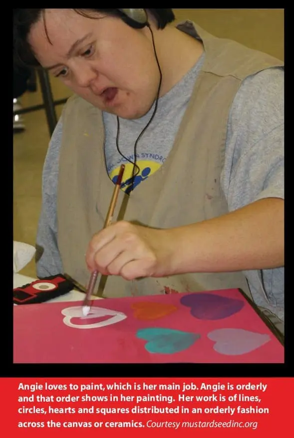 Angie painting hearts on a canvas while wearing headphones.