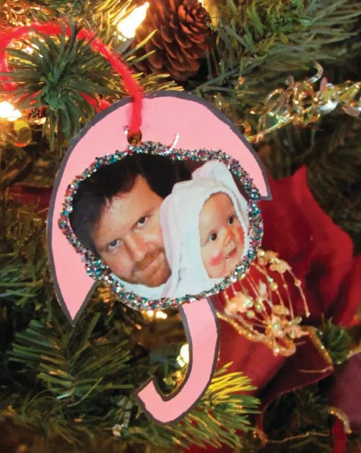 Handmade umbrella-shaped Christmas ornament featuring a photograph of a person and a baby hanging on a tree.