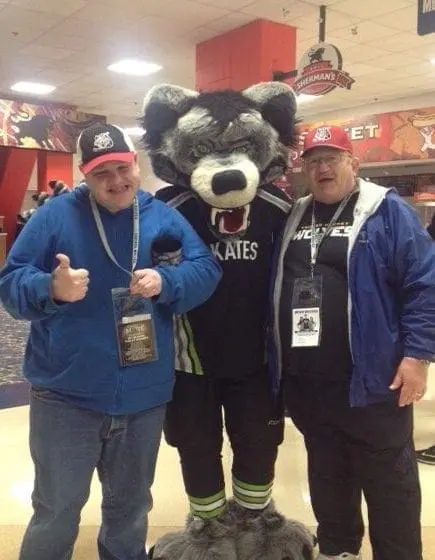 Two men pose with a mascot named Kates.