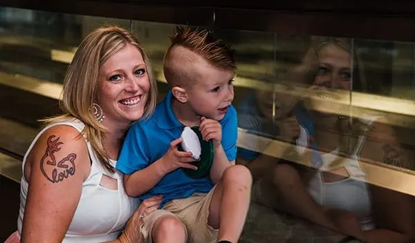 Woman and child sitting on a bench in front of a glass display case.