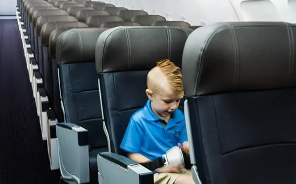 Child sitting in a row of airplane seats.