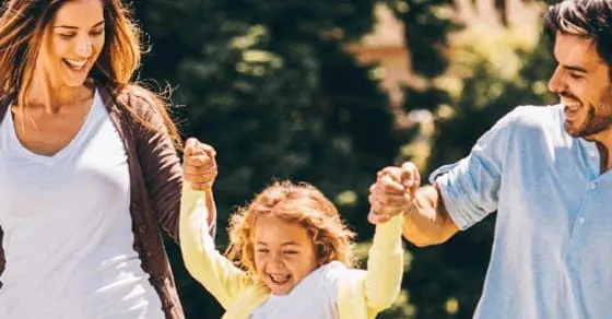 A smiling family walks together outdoors.