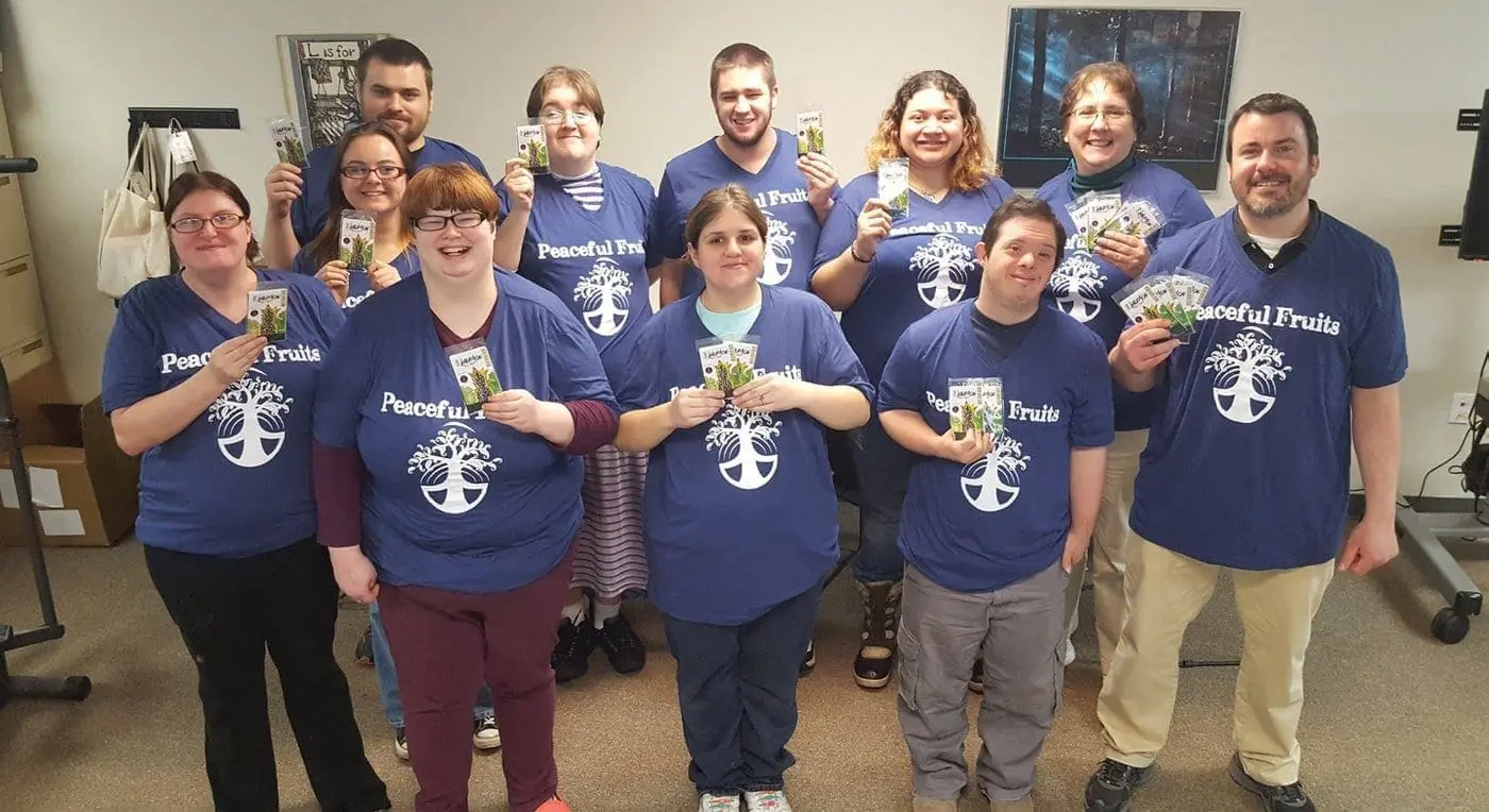 A group of people wearing matching t-shirts stand together holding up products.