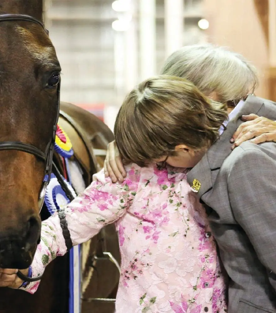 Kathy Saunders hugs her son Evan Saunders next to their horse Nikki.