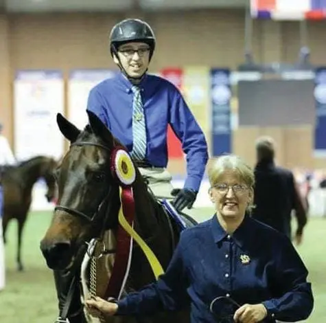 Kathy Saunders and Evan Morgan Saunders on their horse Nikki with a ribbon.