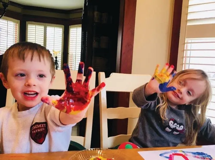 Two children with painted hands at a table