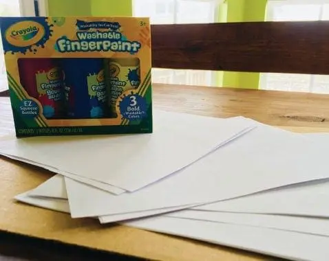 Box of Crayola Washable FingerPaint on a table with blank paper.