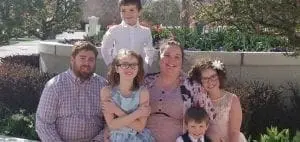 Family poses for a photo outdoors in front of a building.