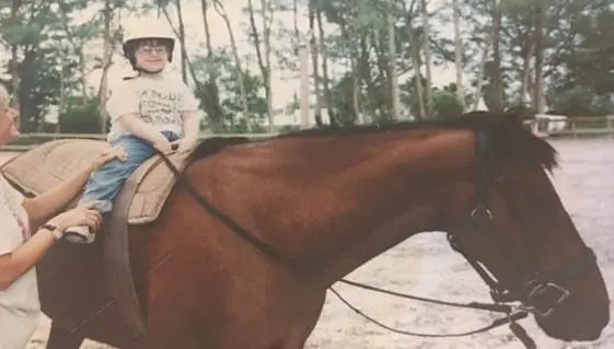 Joey Petruzzi rides a horse with an instructor.